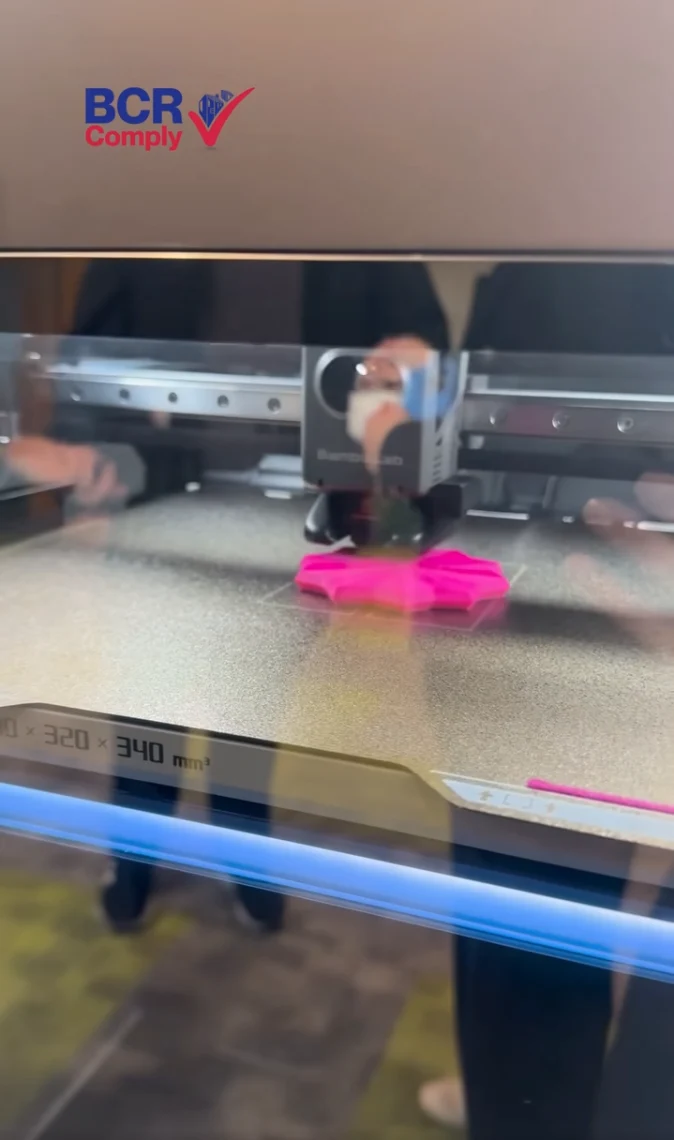 A 3D printer producing a pink object on its print bed
