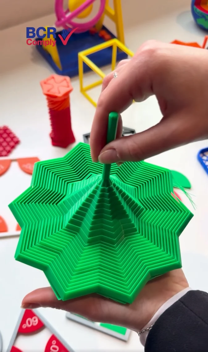 Hands demonstrating a green layered geometric object